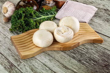 White champignon mushrooms heap over board