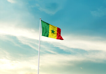 Senegal flag is waving on a tall flagpole among the clouds. Senegal national flag for independence day.