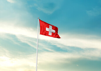 Switzerland flag is waving on a tall flagpole among the clouds. Switzerland national flag for...