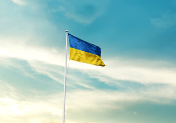 Ukraine flag is waving on a tall flagpole among the clouds. Ukraine national flag for independence day.