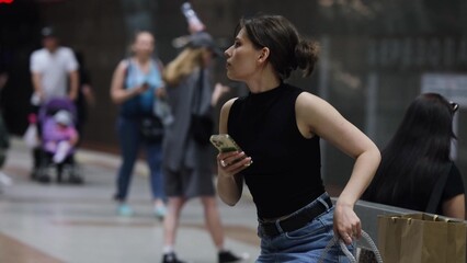 A beautiful brunette is waiting for the train to arrive at the metro station.