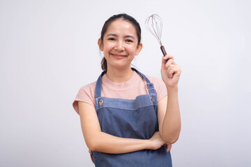 A smiling woman in an apron holds a whisk, ready to cook or bake, conveying a sense of enthusiasm...