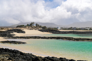 Turquoise waters and volcanic rocks in El Cotillo village, La Concha beach, Fuerteventura