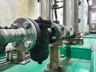 A detailed close-up of a large industrial pipe and a Y-strainer with flanges. The heavy-duty...
