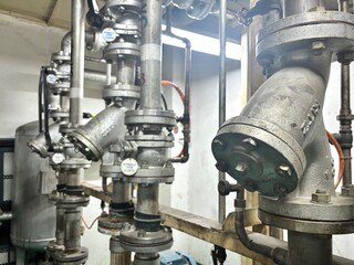 A detailed close-up of a complex network of industrial pipes and heavy-duty flanges in a factory or...