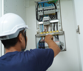 Fototapeta premium Electrician working checking a switchboard with fuses