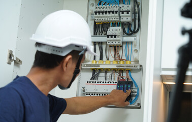 Electrician working checking a switchboard with fuses