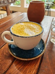 Golden latte in a ceramic cup on a wooden table in a cafe setting