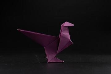 Paper dinosaur on a black background. Origami animals. Paper crafts.