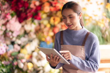 Asian florist woman uses tablet managing flower shop business improving customer service modern...