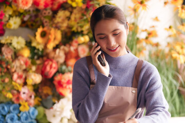Asian young adult woman florist manages flower shop business professional takes customer orders via...