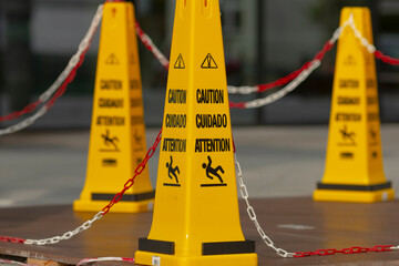 Three bright yellow caution cones are securely chained together in a line, serving as a visible...