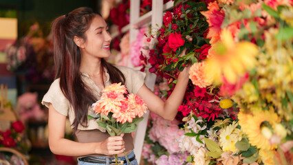Asian woman selecting vibrant flowers in flower shop happy customer finding beautiful bouquet...