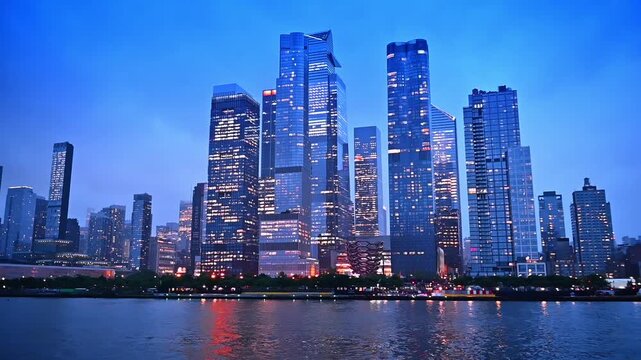 Stunning beautiful modern high-rise architecture of modern New York with lights on in the windows. Low angle view from the river at dusk time.