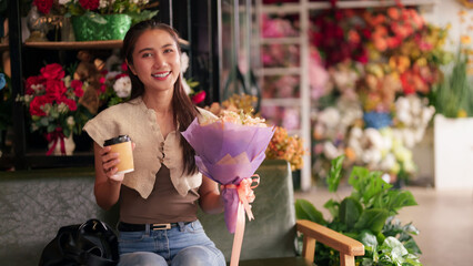 Fototapeta premium Asian woman customer smiling holding fresh flower bouquet coffee cup inside vibrant flower shop purchasing beautiful floral arrangement retail store happy moment