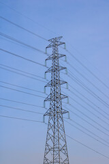 High-Voltage Power Lines and Transmission Tower Against a Clear Blue Sky