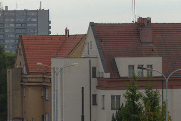 A long row of charming houses featuring vibrant red tile roofs nestled in an urban city...
