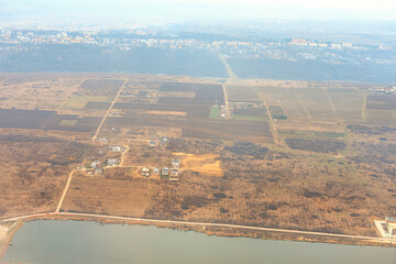 River forms a natural boundary, separating the cultivated fields and residential areas. Meticulously planned layout of farmland and housing developments stretches across the vast expanse