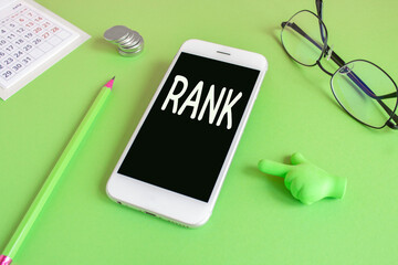 Rank - marketing concept on the mobile phone screen. Beautiful green background. Toy hand. Glasses,...