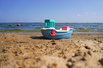 Colorful toy boat resting on sandy beach by the sea