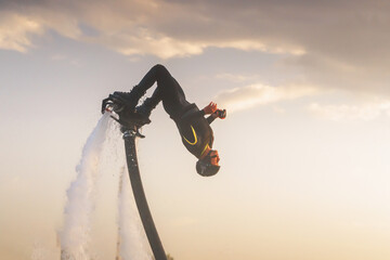 Athlete flyboarder doing close-up stunts. Exciting flyboarding experience at sunset showcasing...