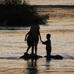 shadows of children playing in the water in the evening