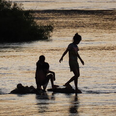 shadows of children playing in the water in the evening