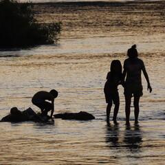 shadows of children playing in the water in the evening