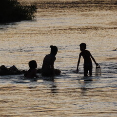 shadows of children playing in the water in the evening