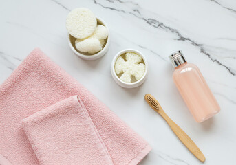 pink towel with natural toothbrush and skincare products on marble background

