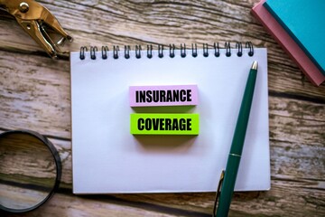 The words INSURANCE COVERAGE are written on a sticky note above a notebook. A beautiful wooden...