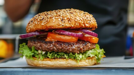 A mouthwatering burger with a sesame seed bun, juicy beef patty, fresh lettuce, tomatoes, and red onions, ready to be enjoyed.