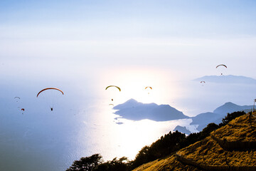 Group of paragliders flying above mountains and sea in Oludeniz Turkey 19 August 2024