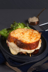 Brioche Croque Monsieur classic French sandwich, essentially a grilled ham and cheese sandwich on black background with copy space