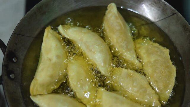Gujhiya a dessert being crispy fried in oil