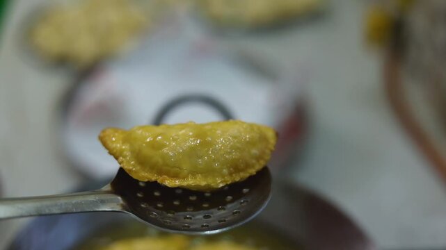 Gujhiya a dessert being crispy fried in oil