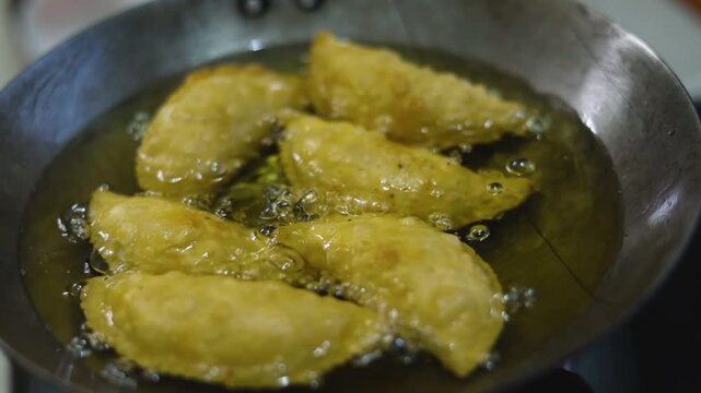 Gujhiya a dessert being crispy fried in oil