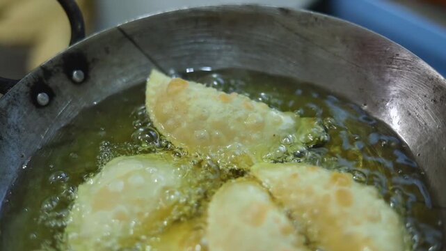 Gujhiya a dessert being crispy fried in oil