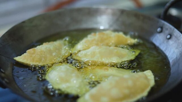 Gujhiya a dessert being crispy fried in oil