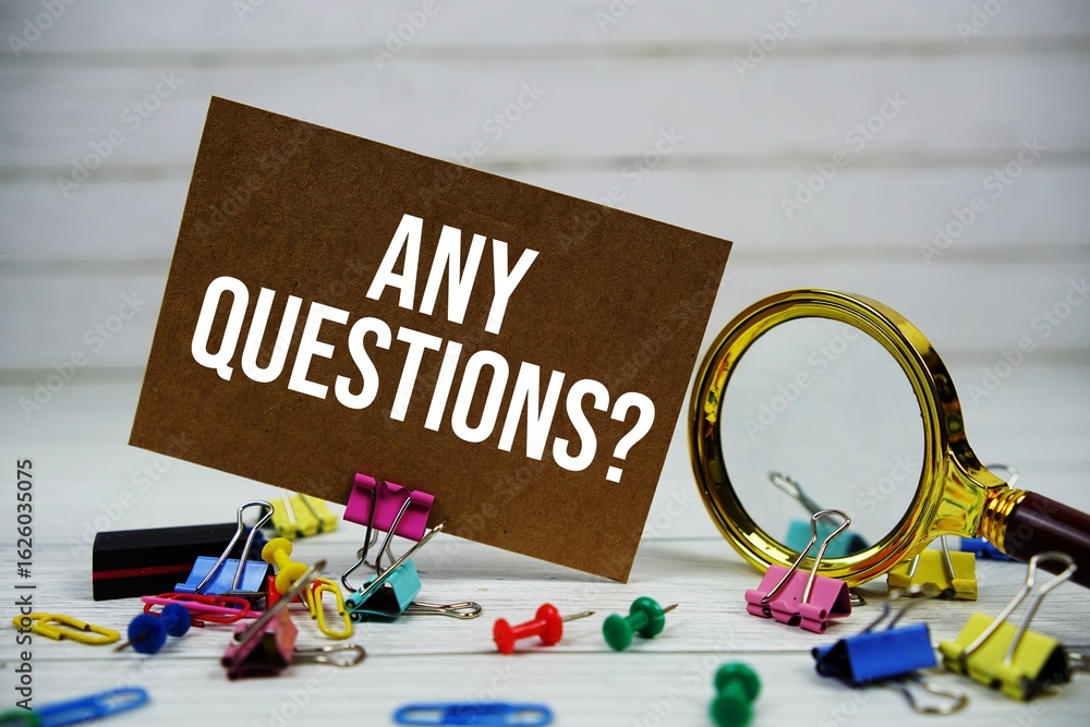 Poster any questions? text on paper card with magnifying glass and stationary on wooden background