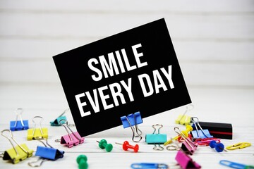 Smile Every Day text on paper card with stationary on wooden background