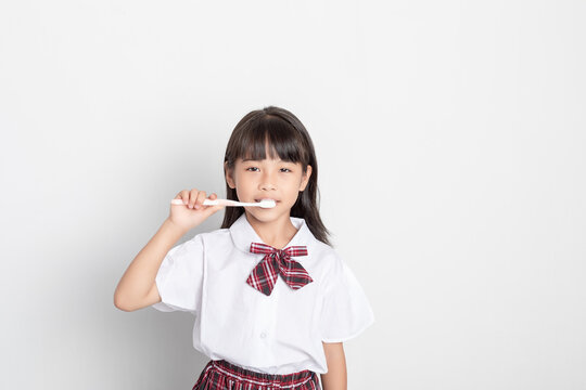 A Chinese elementary school girl is brushing her teeth.