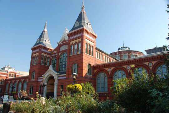 The Smithsonian Castle in Washington, D.C., with its iconic red sandstone facade and garden foreground under a clear blue sky