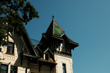 A historic building in Palic, Serbia, with a green and orange patterned roof and a small clock...