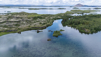 pittoreske Drohnenaufnahme des Sees Myvatn auf Island, Wolken spiegeln sich im Wasser, man sieht...