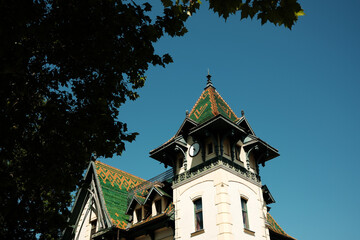 A historic building in Palic, Serbia, with a green and orange patterned roof and a small clock...