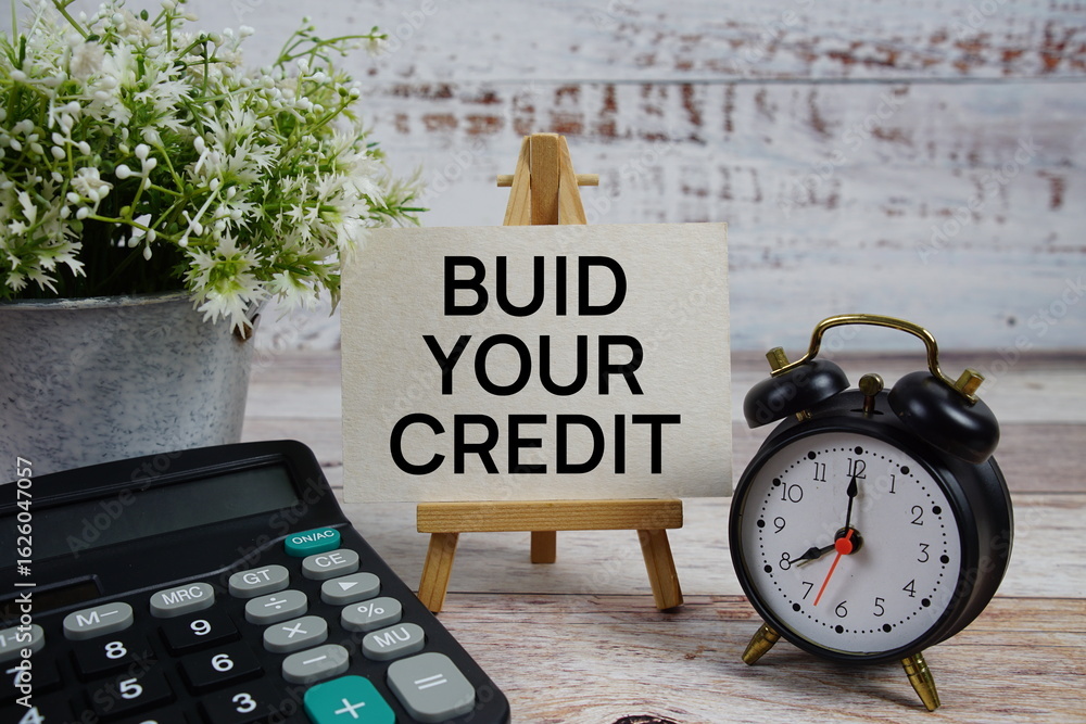 Poster build your credit text with alarm clock and calculator on wooden background