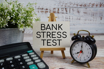 Bank Stress Test text with alarm clock and calculator on wooden background