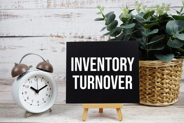Inventory Turnover text with alarm clock on wooden background