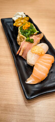Sushi on a black plate on a wooden table